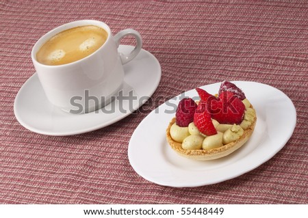 Little white espresso coffee cup and small berry tart over checked table-cloth background