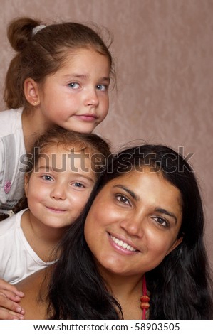 Young mother and two little sisters over defocused wallpaper background