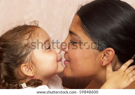 Young mother and her little daughter over defocused wallpaper background