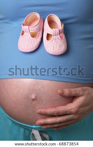 Pregnant woman profile with tiny shoes in the hands over white background