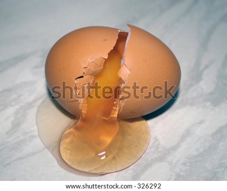 An broken egg spilling onto a marble surface
