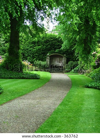 A path through a beautiful garden leading to an ancient garden bench