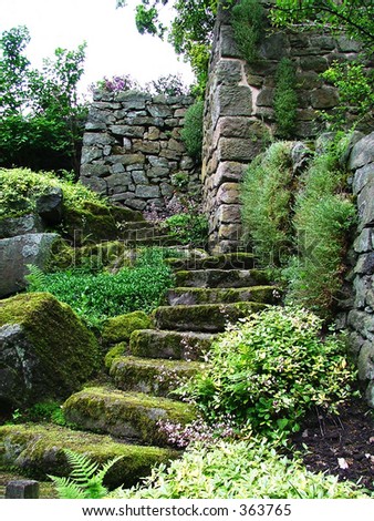 Lichen covered ancient steps lead to a ruined building in a beautiful garden