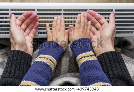 Mother and son heating up a hand in front of an electric heater