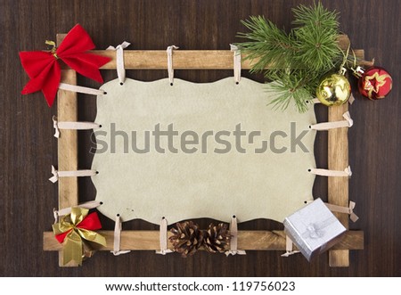 Picture frame with blank canvas space decorated with Christmas baubles, bell, ribbon, tree branch and cones on wooden board background