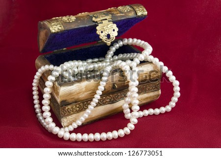 Jewelry box with pearl necklace on red background