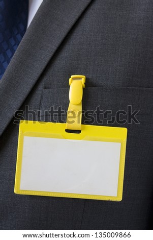 Close up image of a blank badge or pass on dark business suit with empty space for design