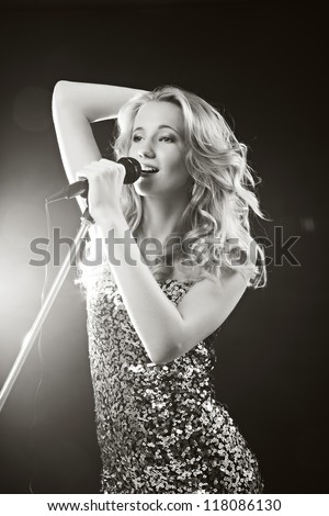 Portrait of an attractive teenager girl  singing with microphone. Black-white image