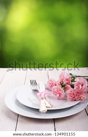 Plate with silverware on wooden table over green bokeh background