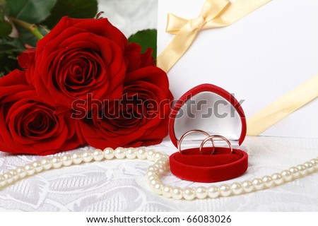 stock photo Wedding rings in box against bouquet of red roses and