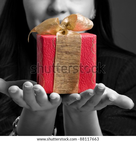 Young woman holding gift against dark background. Black-white image