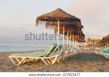 Beach lounge chair and beach umbrella at lonely sandy beach. Costa del Sol (Coast of the Sun), Malaga in Andalusia, Spain