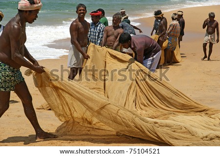 KOVALAM, INDIA - MARCH 14: Kovalam, Kerala, South India,  March 14, 2011.  Fishermen are pulling their fishing net in combined work out of the sea