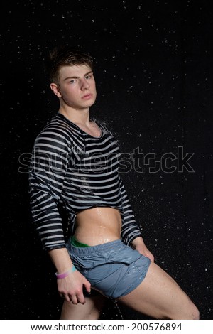 Young man potrait in wet shirt on black background