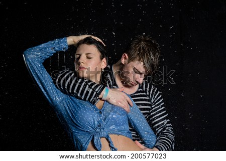 Young beautiful couple portrait in wet shirts on a black background