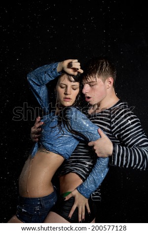 Young beautiful couple portrait in wet shirts on a black background