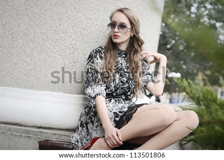 Beautiful woman in glasses sitting at column