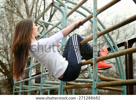 Girl on the wall bars on the playground
