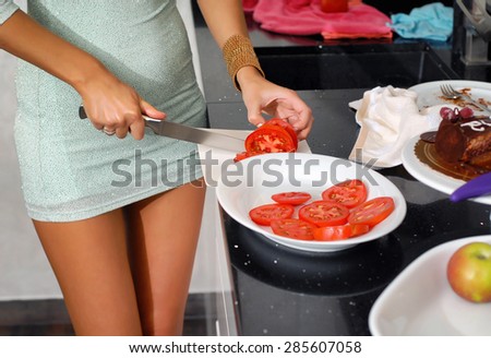 A woman prepares a salad of tomato