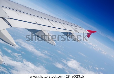 Blue sky in clouds under wing of aircraft in fly