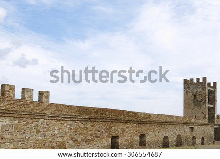 Crimea, Sudak Genoese fortress, ancient fortification of middle ages, defensive castellation stone wall  and tower closeup against blue cloudy sky
