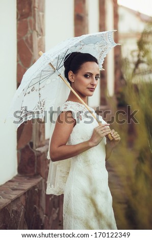 Beautiful bride with stylish make-up in white dress and umbrella