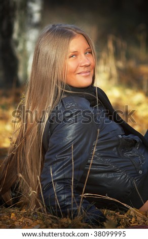 Girl with long hear sit on autumn ground