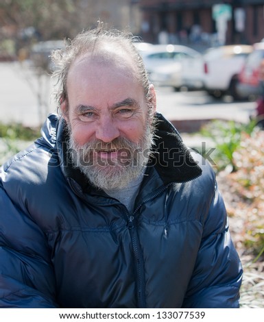 Portrait of happy homeless man outdoors during the day.