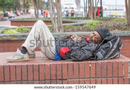 African american homeless man sleeping outside on bricks