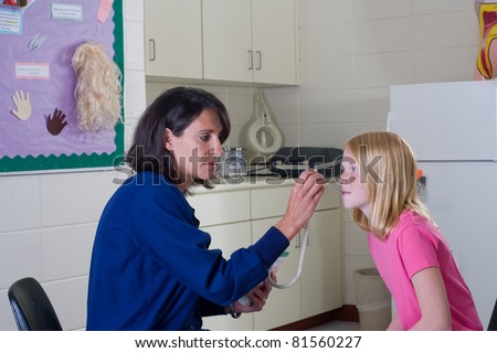 School nurse checking temperature of student patient.