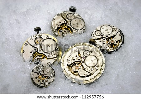 Metal clock mechanisms lie in the snow