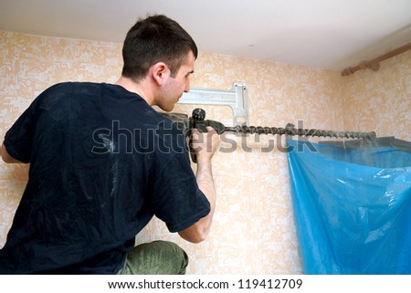 real photo of installation of the conditioner, the worker drills a hole in a wall