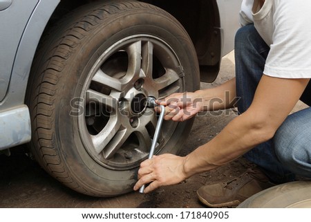 The man changes the punctured wheel of the car.