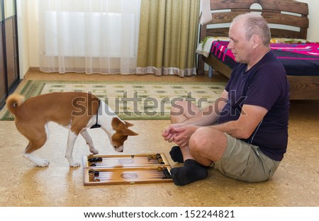 Young dog and mature man playing backgammon