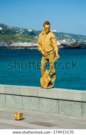 Yalta, Ukraine - May 25, 2013: Human Statue (Live Artist As Guitarist) On The Sea-Front Earn Some Money Letting Campers To Take Photographs With Them.