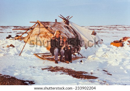 Chukchi Peninsula, USSR - May 1983: Soviet tourist (caucasian man) having contact with kid of the indigenous people while visiting their remote station in tundra.