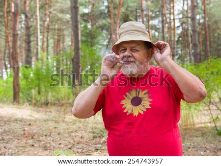 Senior man tasting new home-grown tobacco with cigarette rolled by himself