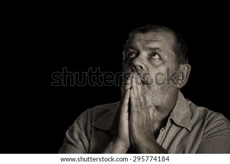 Very emotional sepia toned image of a praying senior man looking up
