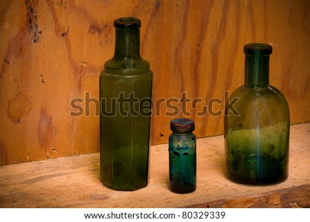 Still Life with differently shaped glass bottles on an old drugstore shelf.