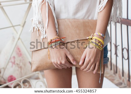 Model with bracelets holding a purse