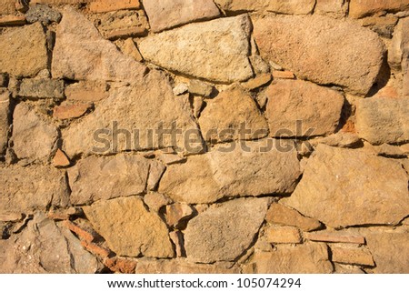 Background image of an antique wall made of stones recently repaired with bricks.
