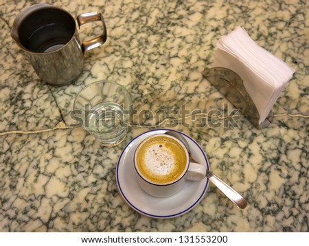 Cup of coffee and water on marble table.
