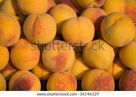 A background of tiled fresh yellow peaches.
