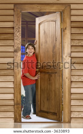 Boy opening a wooden door in front of his home