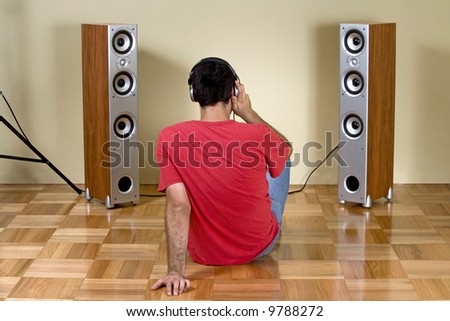 Young man listening music with earphones and modern loudspeakers