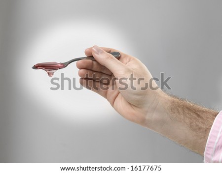 Male hand with spoon of medicine