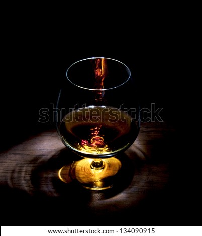 snifter of cognac in elegant glass. black background