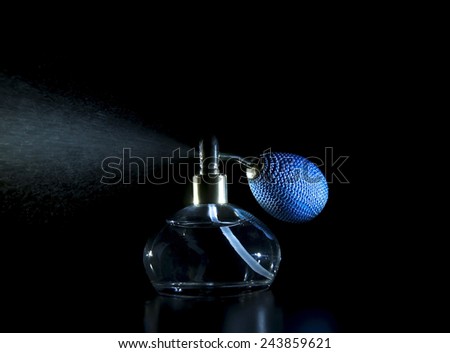 antique perfume bottle with effect of perfume spray on black background