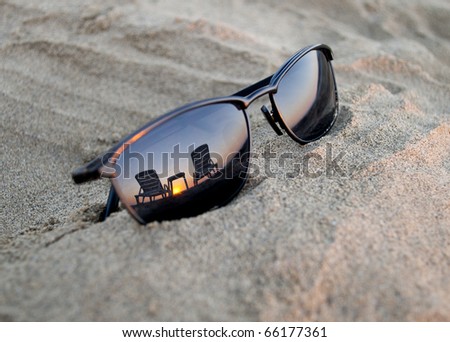 Sun-glasses on the seacoast at the sunset (with the reflection of hammock-chairs and a  sunset, shallow DOF)