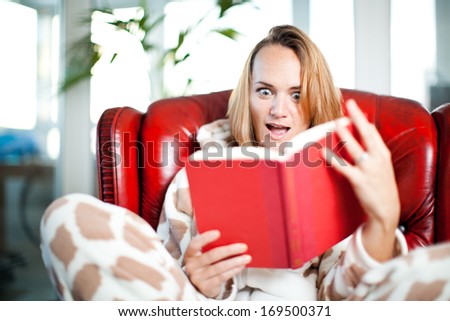 young woman amazed whilst reading a red book